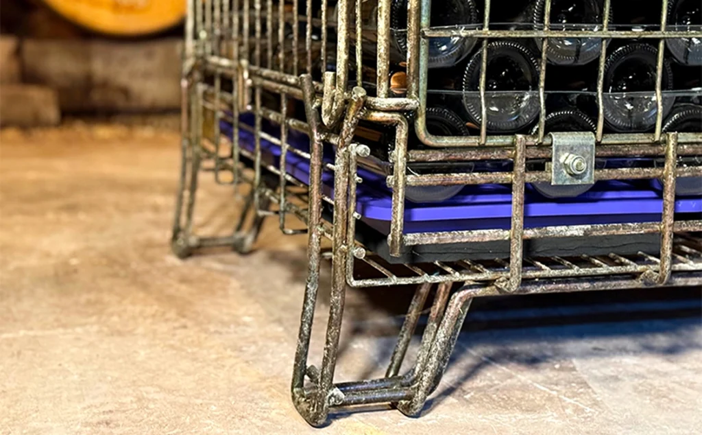 Gros plan sur la balance connectée Botisum placée au fond d'une caisse de bouteilles de vin