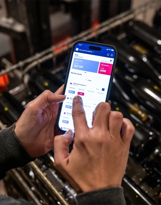 Mains utilisant l'application Botiview de Botisum sur un téléphone mobile dans une cave à vin