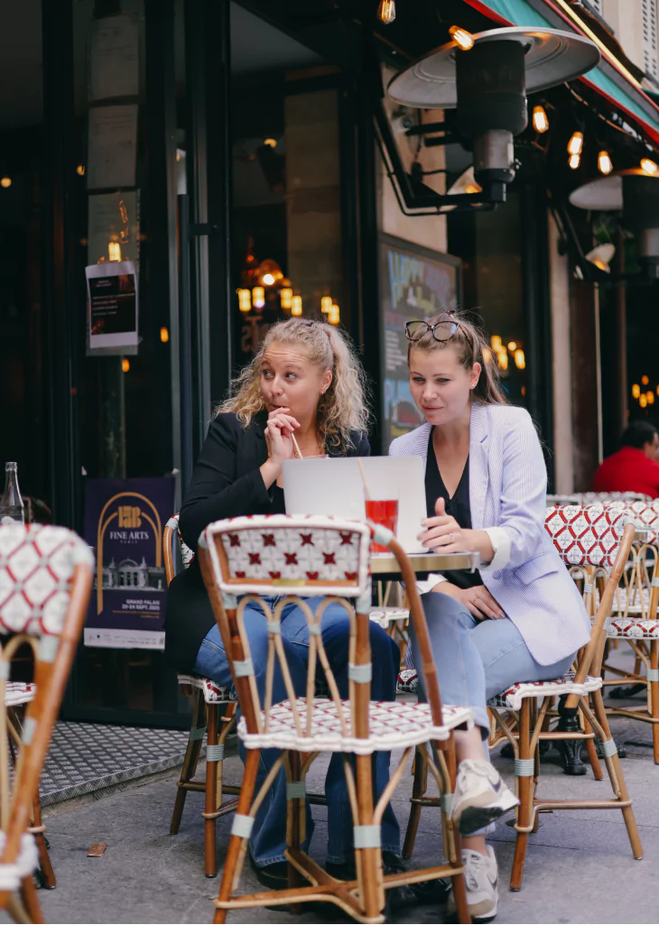 Photo de Delphine et Pauline à la terrasse d'un café en train de travailler sur un ordinateur