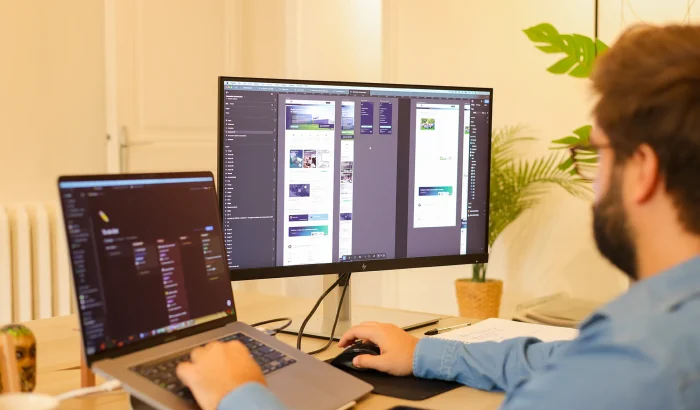 Un solopreneur travaille sur la conception UX/UI et la création de son site internet performant sur un double écran